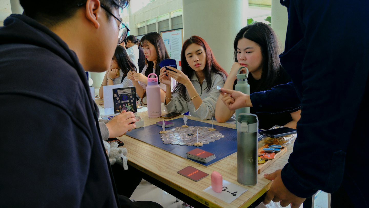 Des amis jouent à un jeu de société autour d'une table en bois.