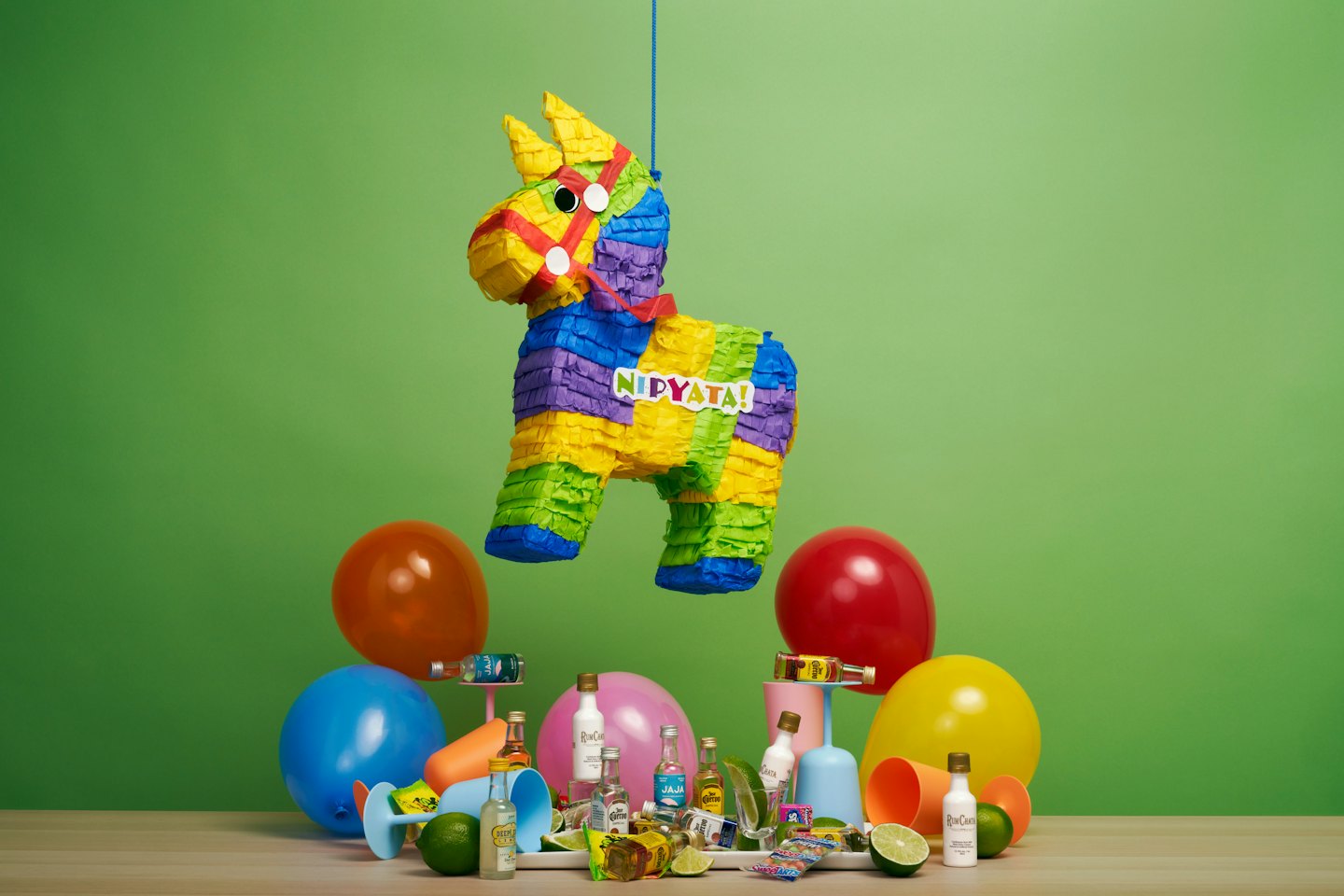 Piñata en forme d'âne entourée de bouteilles d'alcool miniatures et de décorations de fête.