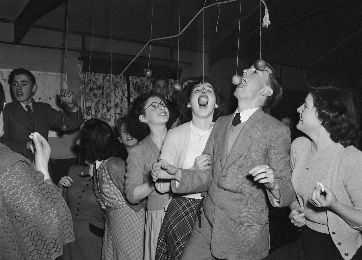 Des adolescents mordent dans des pommes suspendues à des fils lors d'une fête.