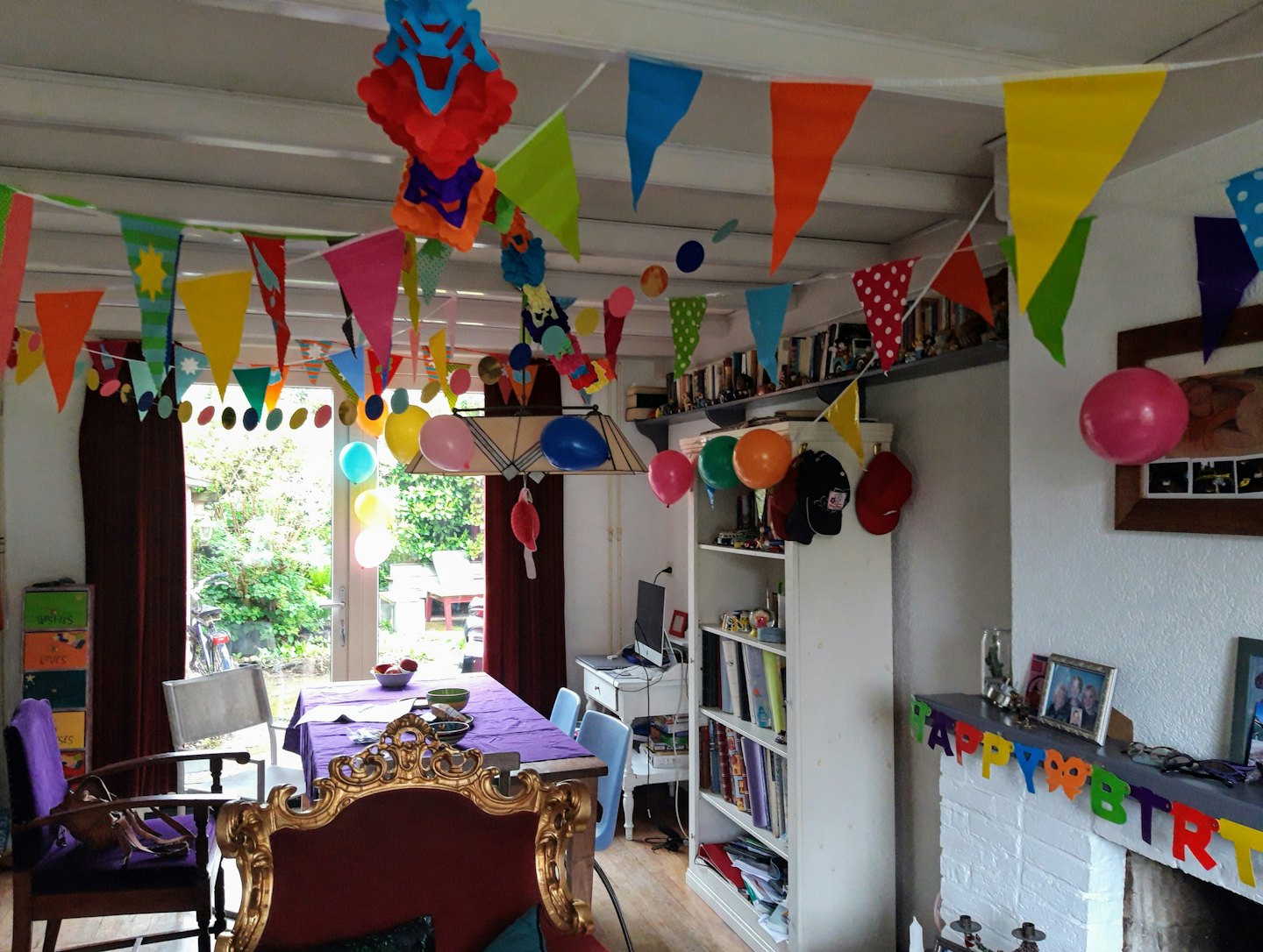 Salon décoré pour un anniversaire avec des bannières et des ballons.