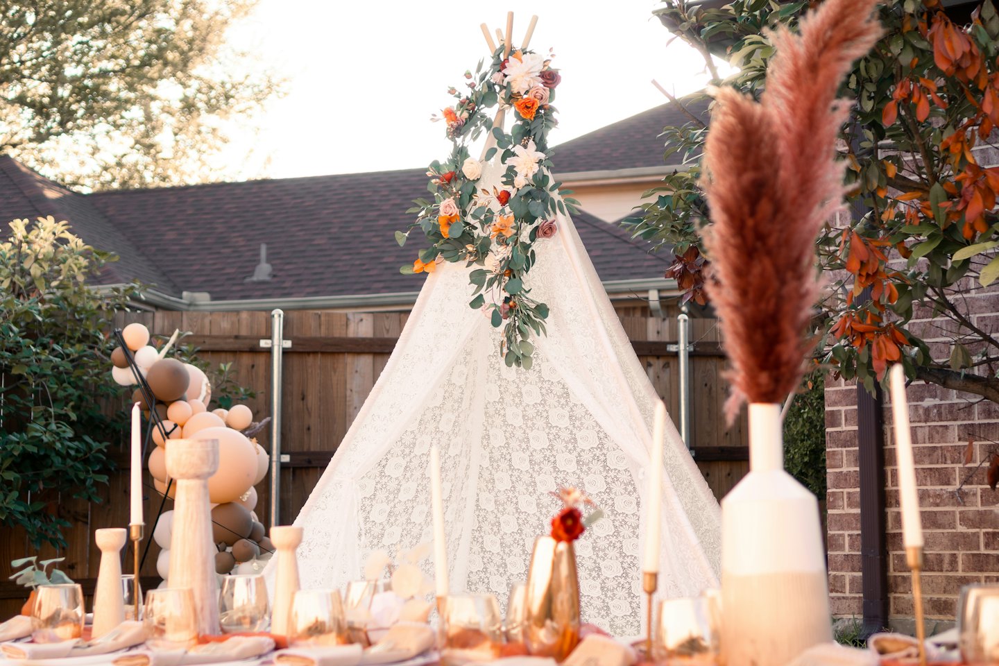 Installation de fête bohème en plein air avec tipi à guirlande florale.