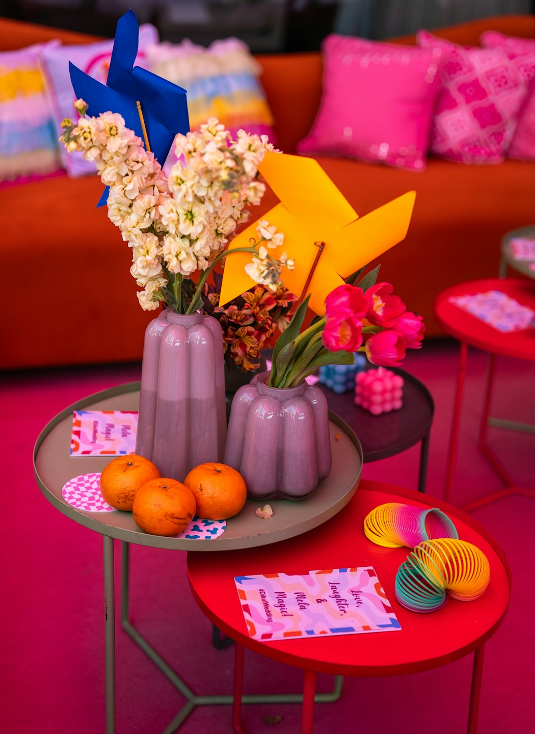 Deux vases de fleurs et des moulinets décorent une table colorée.
